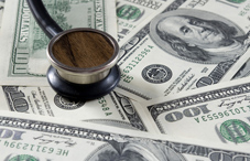 Stethoscope on top of one hundred dollar bills