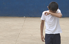 Boy rubbing his eyes with forearm