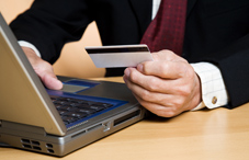 Man typing information from credit card Man typing information from credit card