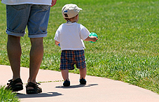 Baby and adult walking on sidewalk Baby and adult walking on sidewalk