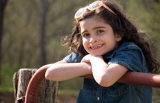 Young girl smiling, leaning against a rail