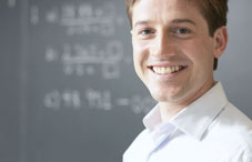 Man smiling in front of a chalkboard 