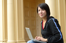 Gil on laptop in front of a building