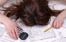 Woman with head buried in tax papers