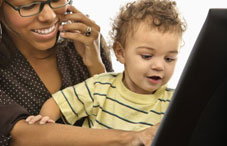 Mother on laptop with baby in lap 
