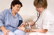 Health care provider checking woman's blood pressure  