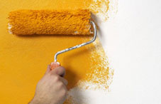 Person painting wall yellow