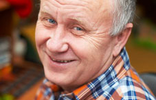 Older man wearing plaid shirt smiling