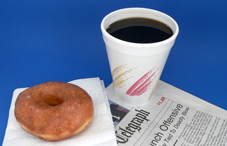 A doughnut, coffee and a newspaper
