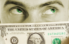 Man with green eyes looking over dollar bill