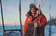 A Yup’ik man stands next to a fish trap on the Kuskokwim River in Akiak, Alaska.