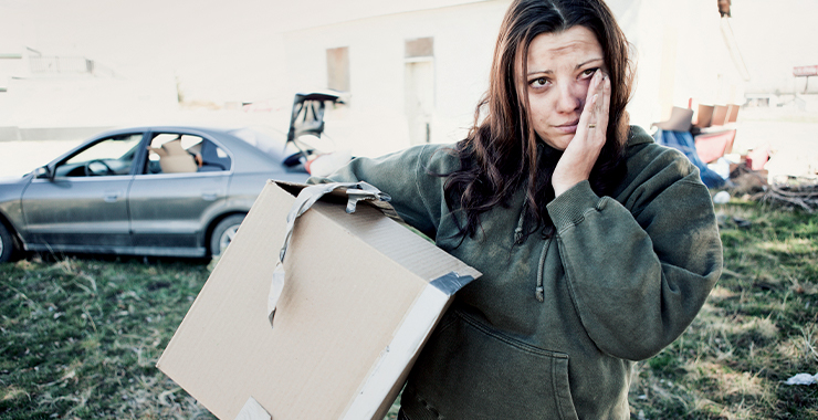 Woman looking distraught with belongings in a box