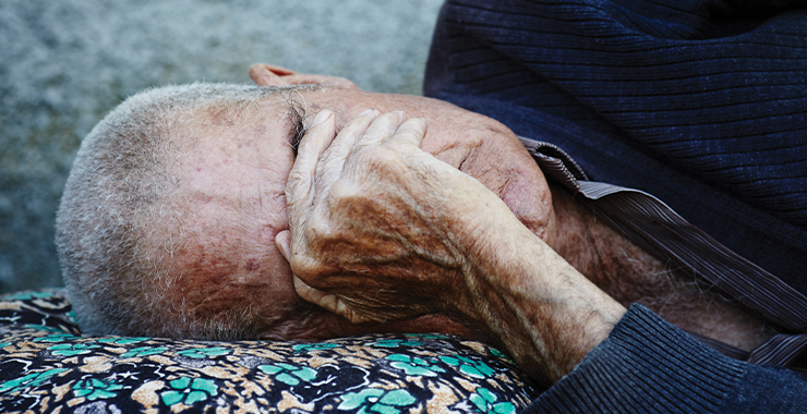 Older man on the ground with his hand over his face