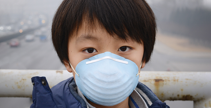 Young child with face mask protecting himself from smog and pollution 