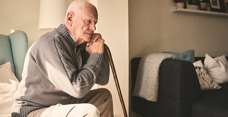 Older man sitting and leaning on a cane