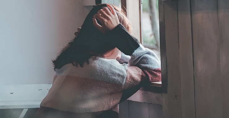 Young woman alone looking out window 