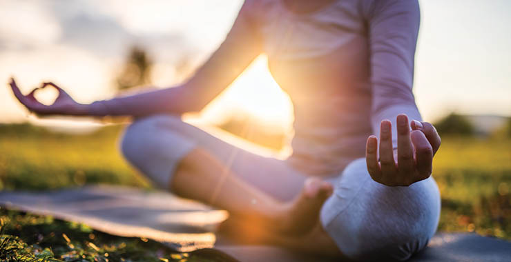 Monitor on Psychology: June; woman doing yoga outside on a mat
