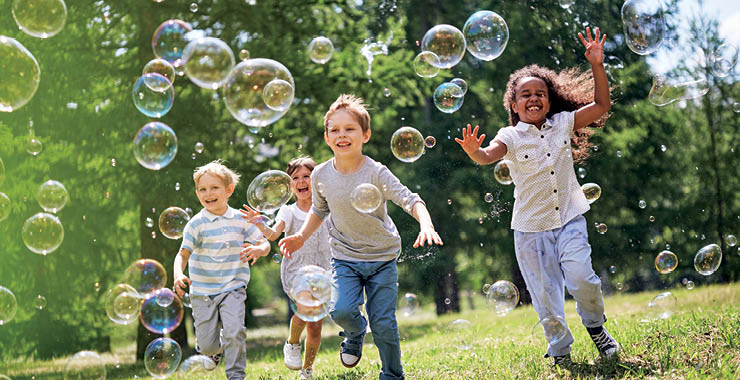 Monitor on Psychology: June; children outside running after bubbles