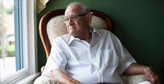 older man staring out a window