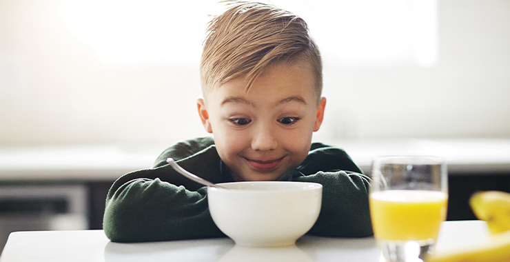 boy with bowl of cereal and juice