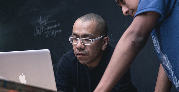 two men looking intently at a laptop screen
