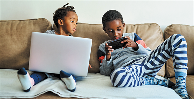 siblings on a couch viewing screens