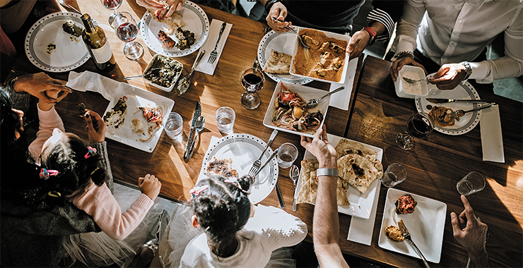 Several people around a dining table with many dishes of food