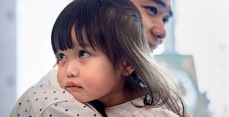 child with her head on her parents shoulder