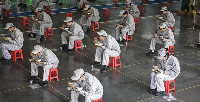 Chinese employees eating lunch on stools 6 feet apart