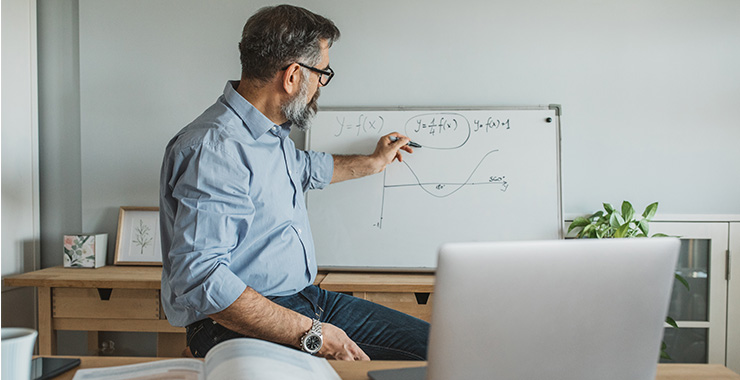 man using dry erase board in front of laptop