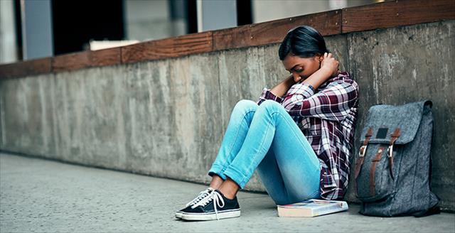 young woman sitting on the ground next to a backpack