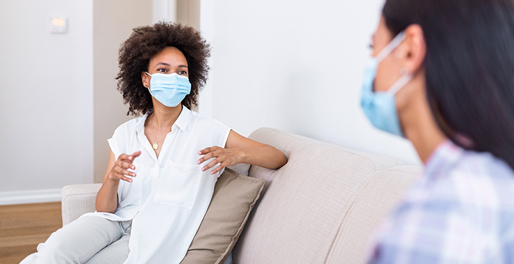 two women talking with masks sitting apart