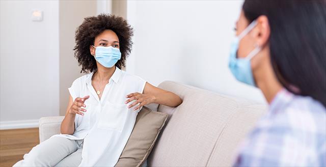 two women talking with masks sitting apart