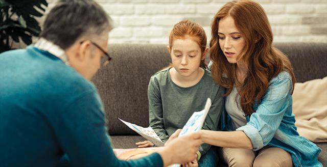 therapist sitting with a mother and her child reviewing paperwork