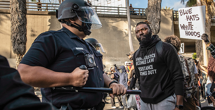 police in riot gear standing in front of a protester