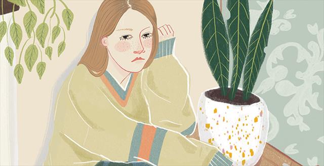 young woman looking sad sitting by a large house plant