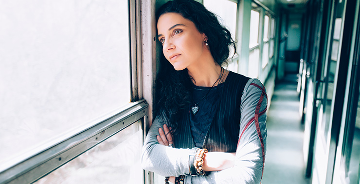 woman with crossed arms looking out a window