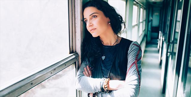 woman with crossed arms looking out a window