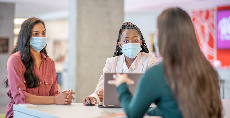 Three women wearing face mask engaging with each other