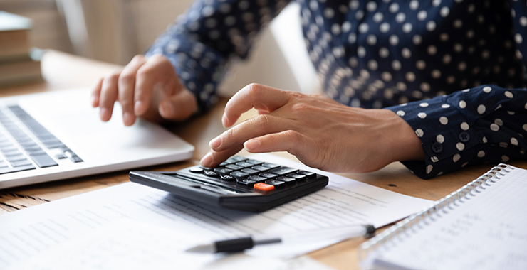 woman in front of a laptop using a handheld calculator