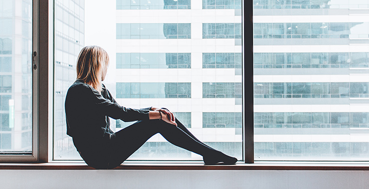 woman sitting alone in front of a window looking out