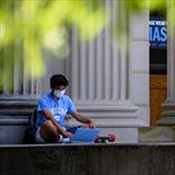 student sitting outside an academic building using a laptop