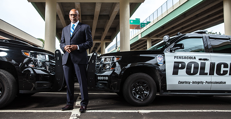 man in a suit standing in front of a police cruiser