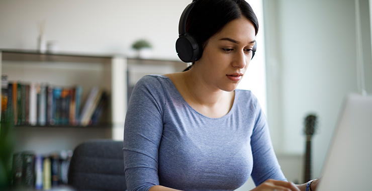 Woman wearing headphones and using a computer