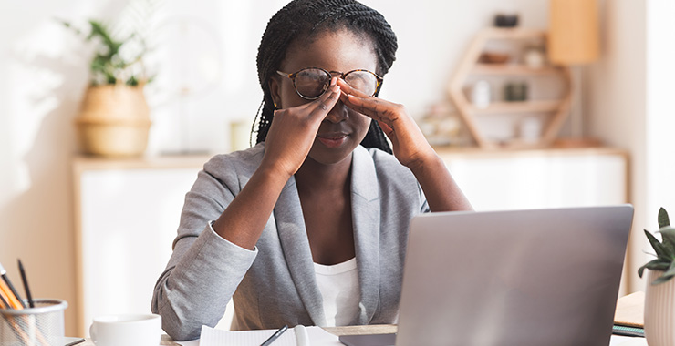 woman looking tired in front of a laptop