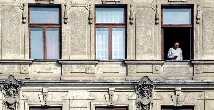 lone man standing in the window of an apartment building