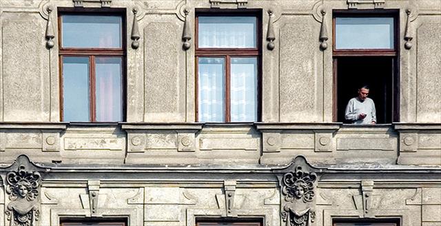 lone man standing in the window of an apartment building