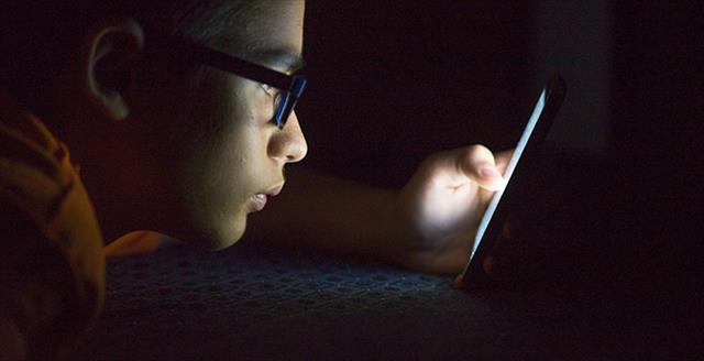 young boy staring at a smart device
