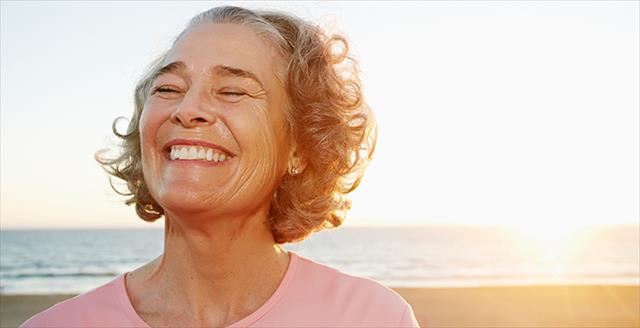 older woman looking very happy on a beach