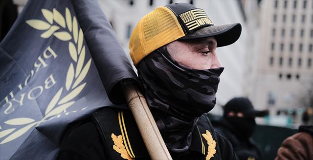 man carrying a Proud Boys flag